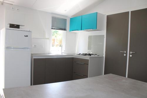 a kitchen with blue cabinets and a white refrigerator at Camping Le Balcon de Chartreuse in Miribel-les-Échelles