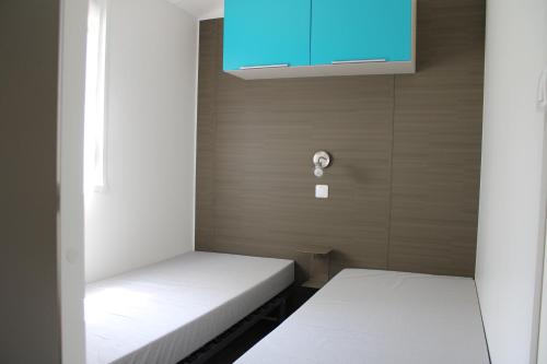 two beds in a small room with a blue cabinet at Camping Le Balcon de Chartreuse in Miribel-les-Échelles