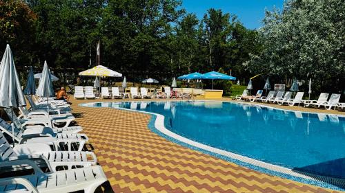 a swimming pool with lounge chairs and umbrellas at Hotel Neva in Kiten