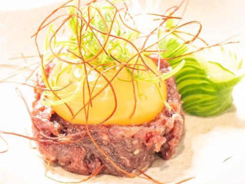 a piece of meat with sauce and vegetables on top at Hotel Sumire ふぐ料理を愉しむ料理宿 in Shimonoseki