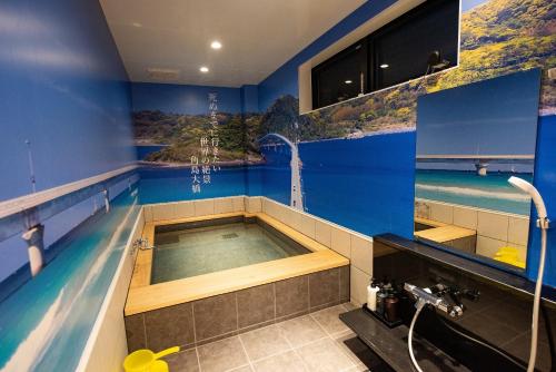 a jacuzzi tub in a bathroom with blue walls at Hotel Sumire ふぐ料理を愉しむ料理宿 in Shimonoseki