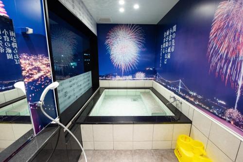 a bathroom with a pool with fireworks in the background at Hotel Sumire ふぐ料理を愉しむ料理宿 in Shimonoseki