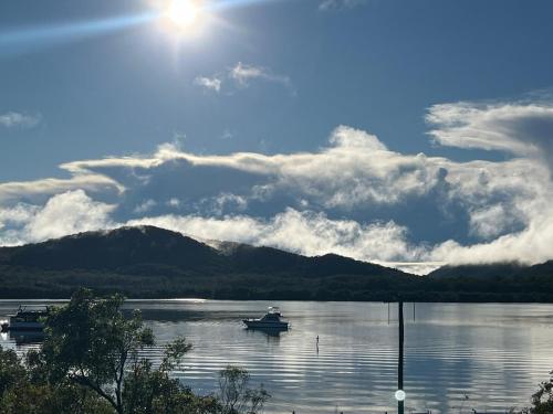 a boat on a lake with mountains in the background at Riverside Retreat in Karuah