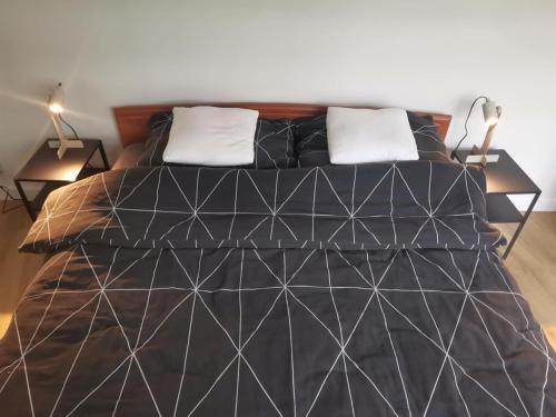 a bed with a black comforter and two lamps at Apartament w Centrum in Kętrzyn