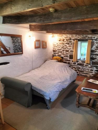 une chambre avec un lit et un mur en pierre dans l'établissement La Maison de Poupée Gîte cosy Monts d'Arrée Bretagne, à Berrien