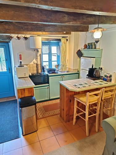 une cuisine avec des placards verts et un comptoir dans l'établissement La Maison de Poupée Gîte cosy Monts d'Arrée Bretagne, à Berrien