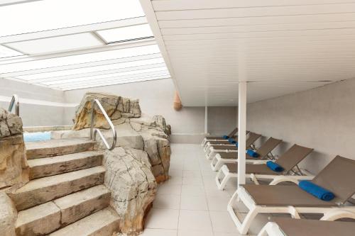 a room with a rock wall and some chairs and stairs at Hotel Best Roquetas in Roquetas de Mar