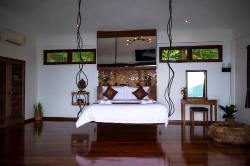 a bedroom with a bed and a mirror in it at Monkey Flower Villas in Koh Tao