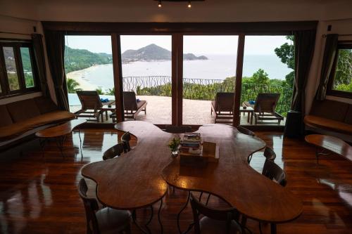 a room with tables and chairs and a view of the ocean at Monkey Flower Villas in Koh Tao