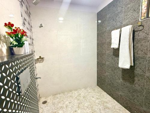 baño con ducha y jarrón de flores rojas en BASTAR by Modern Haven, en Jāmb