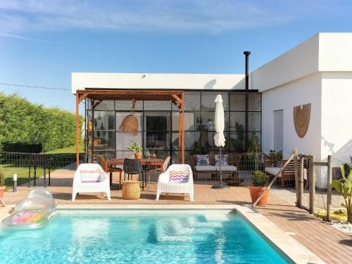 a swimming pool with two chairs and a house at Sunset River Villa, Lisbon in Alcochete