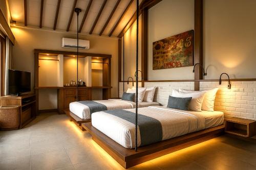 a bedroom with two beds and a flat screen tv at Kaleydo Villas in Gili Trawangan