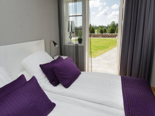 a white bed with purple pillows in a bedroom at Gårdshotellet Påarps Gård in Håcksvik