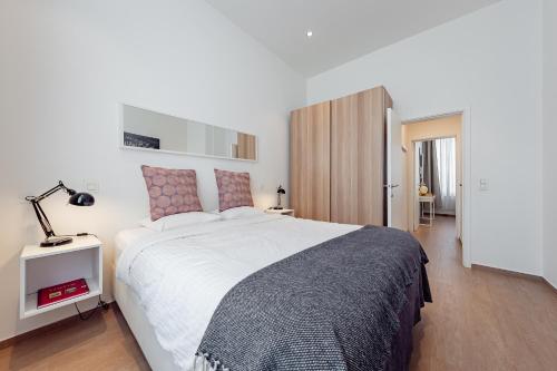 a bedroom with a large white bed and a lamp at Fully furnished and modern flat - Brussels center in Brussels