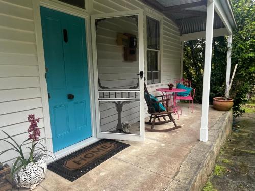 a porch with a blue door and a table and chairs at The Bay Rose in Forrest