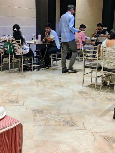 a group of people sitting at tables in a restaurant at Hotel Candor Amigo Airoli Mind Space in Navi Mumbai