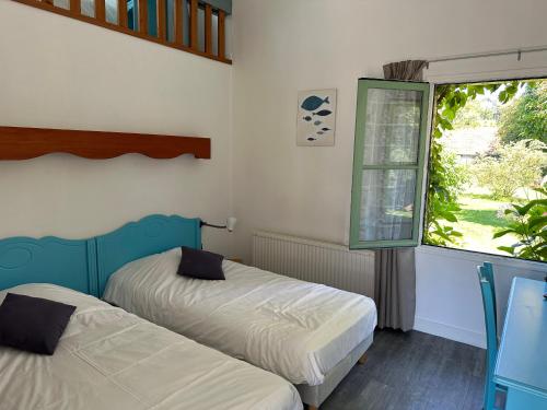 two beds in a room with a window at Logis Hôtel La Demeure du Perron in Quettehou
