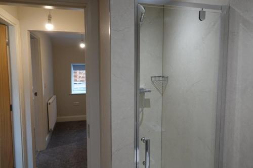 a shower with a glass door in a bathroom at Brocken Brae Cottage in Easby