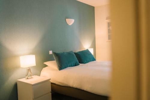a bedroom with a bed with blue pillows and a lamp at Hotel Aigue Marine in Tréguier