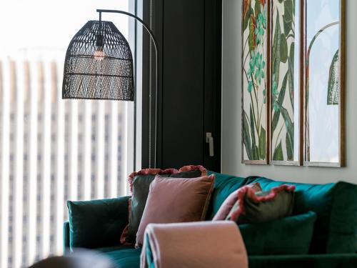 a living room with a green couch and a lamp at Your Perfect Stay luxury Serviced Apartments- City Centre - Better and bigger than a hotel! in Birmingham