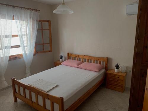 a bedroom with a bed with pink pillows and a window at Martha's home in Nea Vrasna