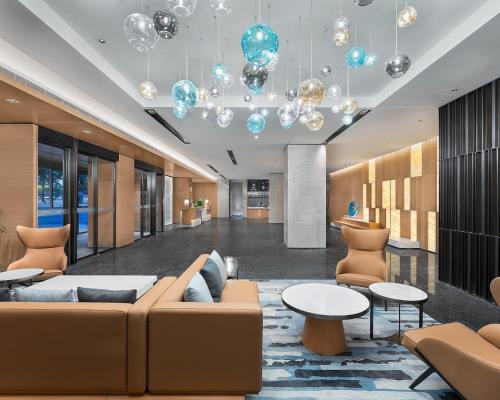a lobby with a couch and tables and chandeliers at Fairfield by Marriott Yining in Yining