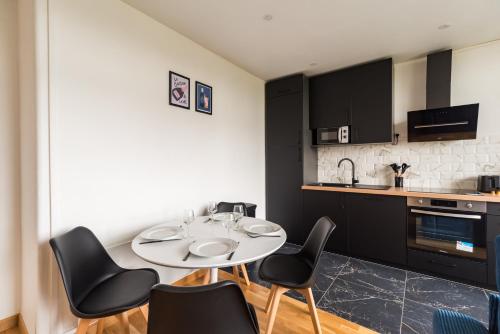 une cuisine avec une table blanche et des chaises noires dans l'établissement Hôtel Lefort - La Bretonne Authentique, à Guingamp