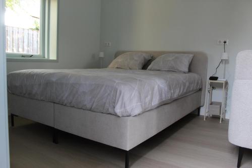 a large bed in a bedroom with a window at De Strandloper Zeeland, Studio nabij strand 3km in Koudekerke