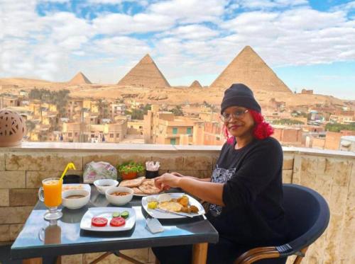a woman sitting at a table with a plate of food at Pyramids View Hills iNN in Cairo