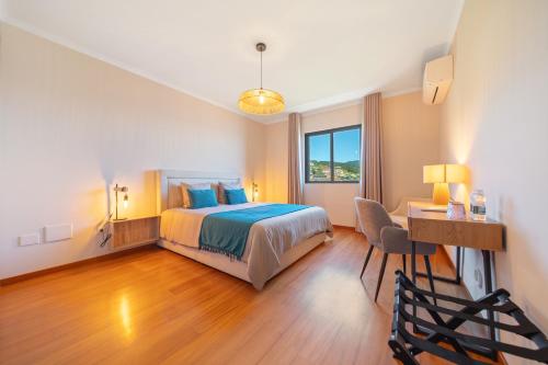 a bedroom with a bed and a desk with a chair at Casa do Mundo Madeira in Gaula