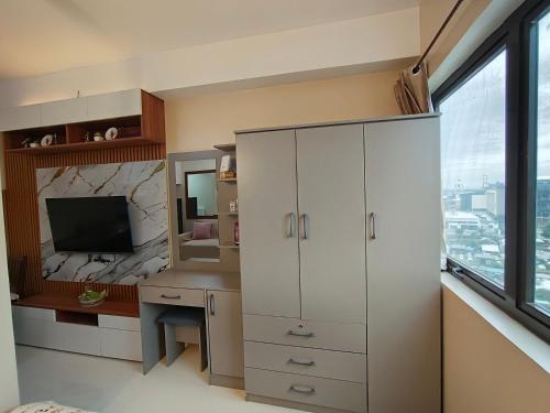 1 dormitorio con un gran armario blanco y TV en Rhiangelo Condo Suite in Cebu City, en Cebú
