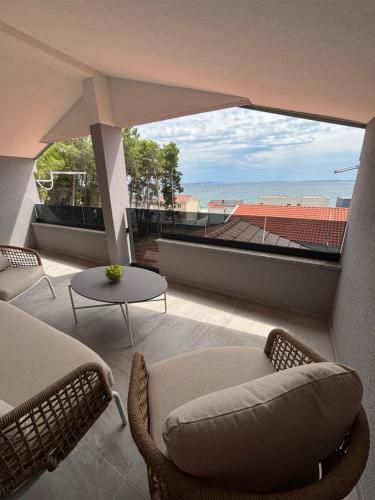 d'un balcon avec un canapé et des chaises offrant une vue sur l'océan. dans l'établissement Apartman Denis, à Vir