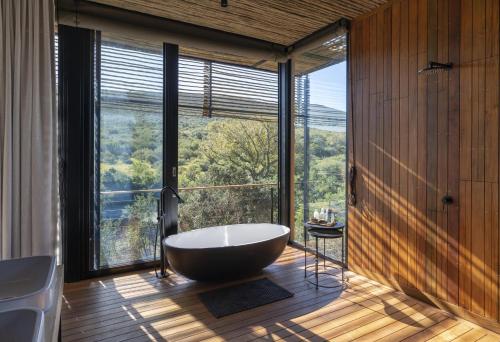 a bathroom with a tub in front of a large window at Shamwari Bayethe in Paterson