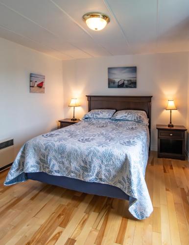 a bedroom with a bed and two lamps on two tables at Gite la Maison Rochefort in Baie-Sainte-Catherine