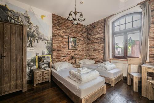 two beds in a room with a brick wall at Stara Przepompownia in Ostrów Wielkopolski