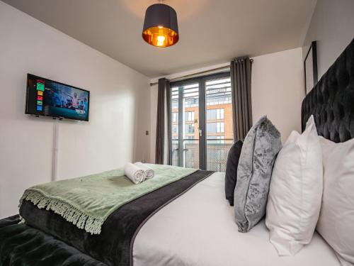 a bedroom with a large white bed with a flat screen tv at Central Birmingham Apartment with Balcony & Netflix in Birmingham