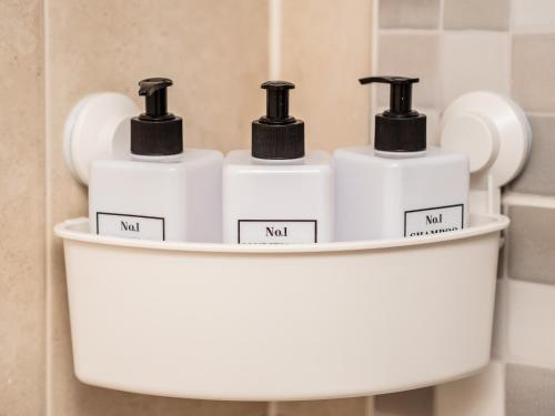 four bottles ofodorizers sit on a shelf in a bathroom at Central Birmingham Apartment with Balcony & Netflix in Birmingham