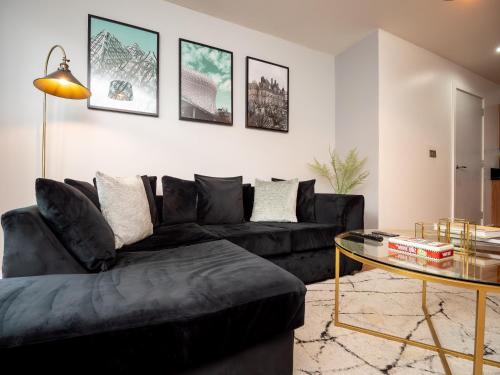 a living room with a black couch and a glass table at Central Birmingham Apartment with Balcony & Netflix in Birmingham