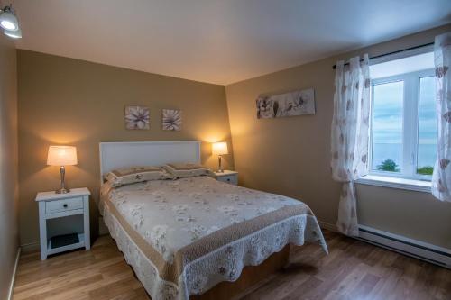 a bedroom with a bed and a large window at Gite la Maison Rochefort in Baie-Sainte-Catherine