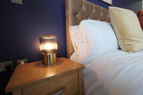a lamp on a wooden table next to a bed at Central Birmingham Apartment with Balcony & Netflix in Birmingham
