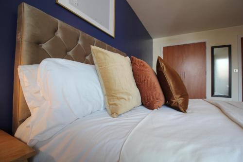 a bed with four pillows on top of it at Central Birmingham Apartment with Balcony & Netflix in Birmingham