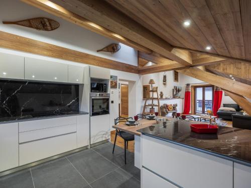 Il comprend une cuisine avec des placards blancs et des plafonds en bois. dans l'établissement Appartement rénové au centre de Megève avec balcon et parking - FR-1-569-137, à Megève