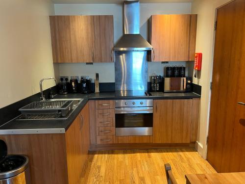 a kitchen with wooden cabinets and a stove top oven at Central Birmingham Apartment with Balcony & Netflix in Birmingham