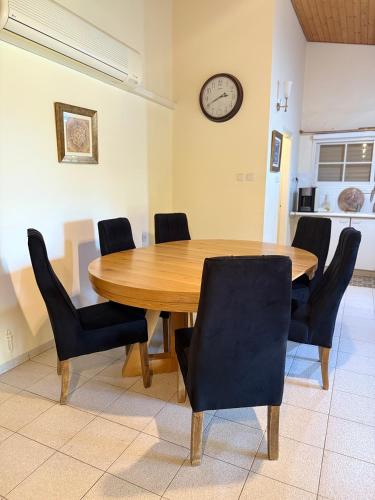 a dining room table with chairs and a clock on the wall at וילה נקודה בכנרת in Had Nes