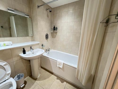a bathroom with a sink and a tub and a toilet at Central Birmingham Apartment with Balcony & Netflix in Birmingham