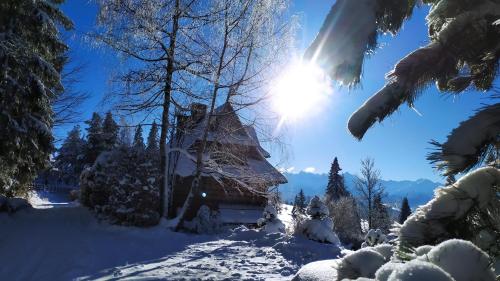 a cabin in the snow with the sun in the background at Dom na Pawlikach in Rzepiska