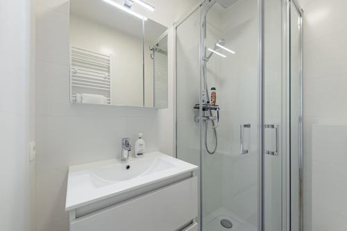 a white bathroom with a sink and a shower at Surreal cocoon in Brussels center in Mellet