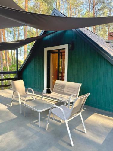 a group of chairs and a table in front of a green building at Daleko od Szosy in Krajęczyn