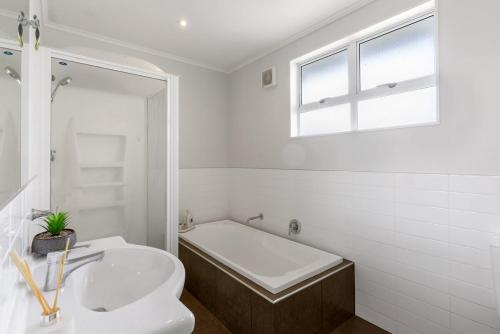 a white bathroom with a tub and a sink at Relax near Auckland city & enjoy in Auckland