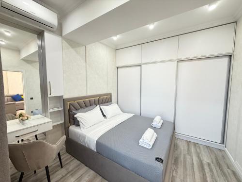 a bedroom with a bed and a desk and a chair at Bay Tash Tower in Bishkek